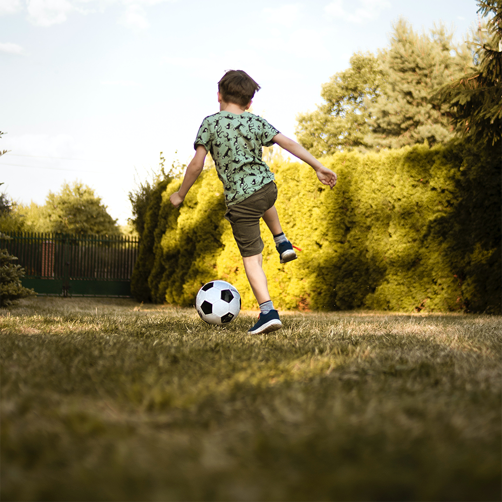 Junge spielt Fußball im Garten