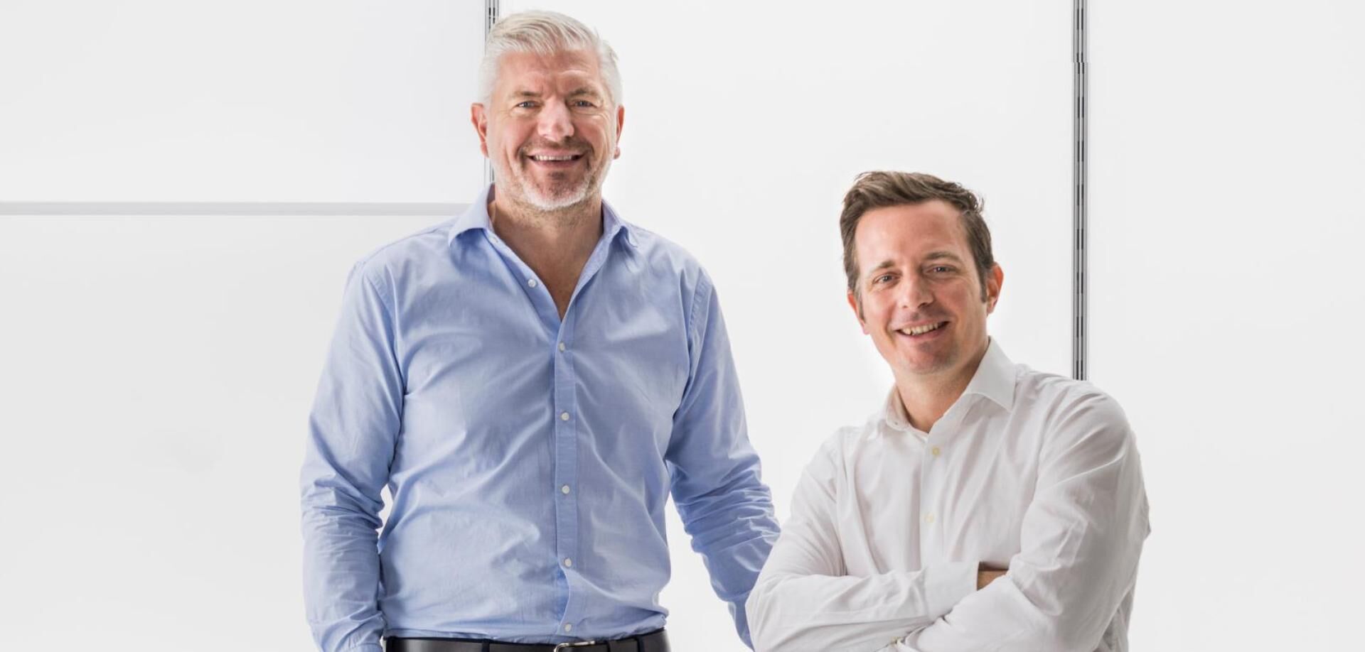 Die beiden CEOs der Firma Pixlip stehen lachend auf weißem Hintergrund