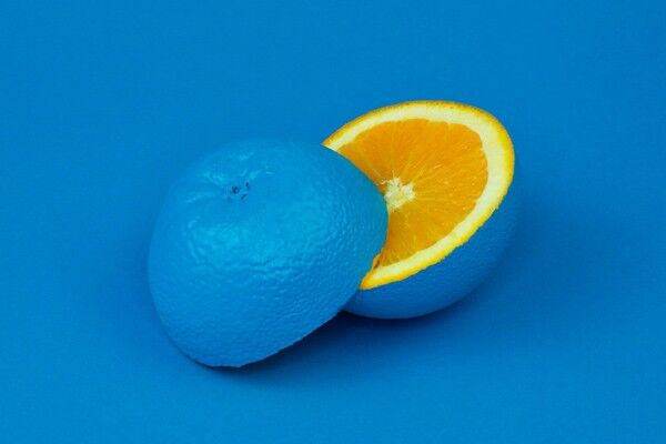 Blaue Orange in zwei Hälften geschnitten auf blauem Hintergrund